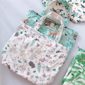 Detailed flat lay of cotton tote bags with forest animal patterns and zipper closure