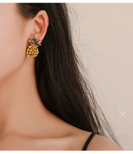 Detailed view of a model wearing sparkling pineapple stud earrings with yellow crystals