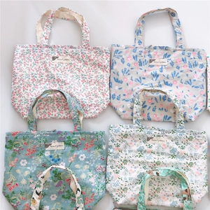 Macro shot of four floral canvas tote bags in pink, blue, green, and beige colors