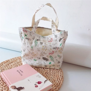 Close-up of floral print cotton handbag with red berries on a woven mat