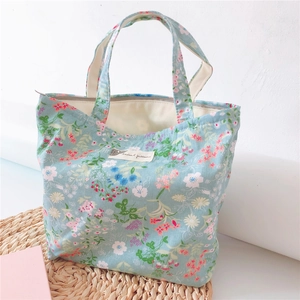 Detail of light blue floral canvas handbag with animal patterns label on woven mat