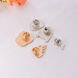 Set of five gold and silver enamel pins with butterfly clutch backs on white surface