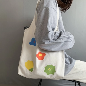 Dettaglio della borsa tote in tela con motivi floreali vivaci indossata a spalla