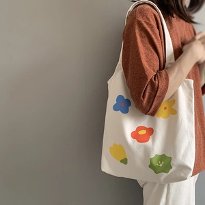 Dettaglio della borsa tote in tela bianca con stampe floreali colorate dipinte a mano