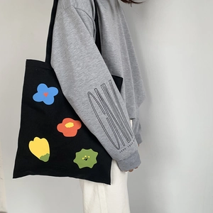 Dettaglio della borsa in tela nera con stampe floreali astratte colorate e tessuto forte