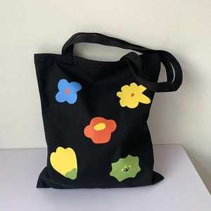 Dettaglio della borsa tote in tela nera con stampa floreale colorata e manici robusti