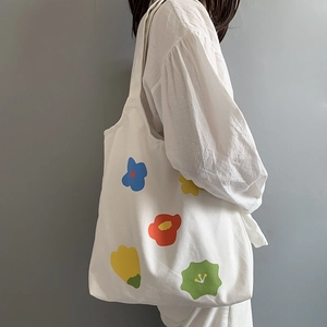 Dettaglio ravvicinato di una borsa tote in tela bianca con vivaci motivi floreali