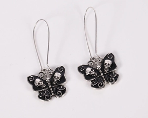 Detailed macro shot of gothic butterfly skull earrings with black enamel dripping