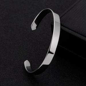 Polished silver titanium steel C-shaped open bracelet on a black jewelry box display