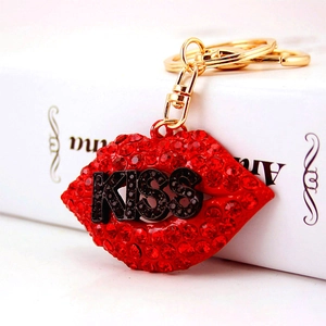 Sparkling red rhinestone kiss lips keychain with gold hardware on a white book
