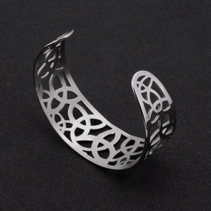 Detalle de brazalete abierto de acero inoxidable plateado con intrincados motivos celtas