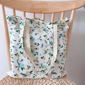 Detail of floral cotton canvas tote bag featuring small blossoms on a wooden vintage chair