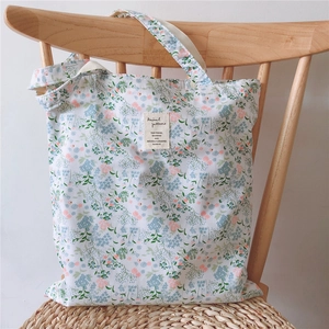 Floral cotton canvas tote bag with shoulder strap hanging on a wooden chair