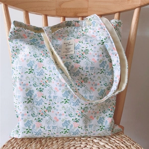 Detailed view of floral canvas tote bag resting on a wooden chair in soft lighting