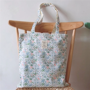 Detailed view of floral canvas tote bag with vintage label hanging on a wooden chair