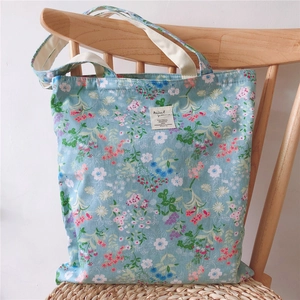 Close-up of floral pattern cotton tote bag with cream straps on a wooden chair