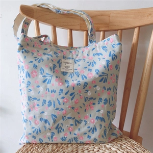 Detail of floral canvas tote bag featuring pink blossoms on light green fabric textures