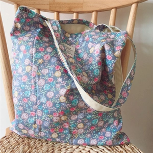 Detail of floral canvas tote bag with rose patterns on a light wooden chair