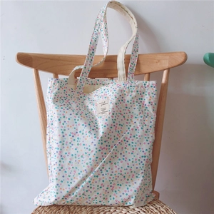 Detail of floral canvas tote bag featuring colorful pixel patterns and woven logo label
