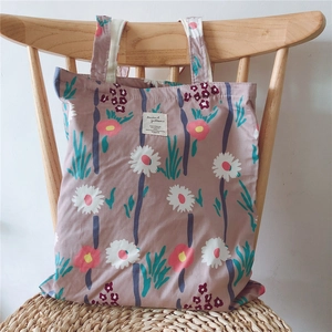 Detail of floral canvas tote bag featuring white label text on pink floral fabric