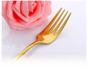Close-up of golden stainless steel dinner fork with mirror polished finish and four tines
