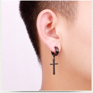 Close-up of black stainless steel cross pendant earring worn by a male model in punk style