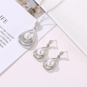 Detailed view of silver water drop necklace and pearl earrings set with sparkling rhinestones