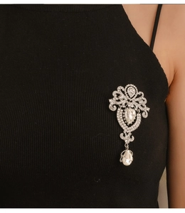 Close-up of a vintage silver-toned crown brooch with clear crystals and a teardrop pendant