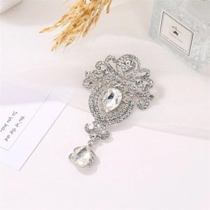 Detailed close-up of a vintage teardrop crown brooch with intricate crystal inlay and silver finish