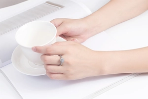 Close-up of a square zircon ring on a hand holding a white coffee cup for a lifestyle view