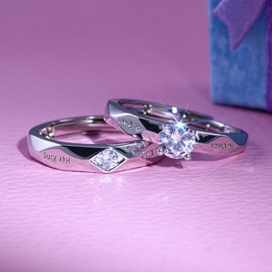 Close-up of silver-plated couple rings engraved with Her King and His Queen text