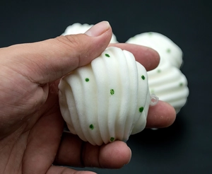 Detailed view of white squishy flower bun keychain with green dots and spiral texture
