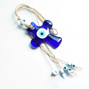 Detail of blue glass evil eye cross ornament with rustic hemp rope and metallic beads