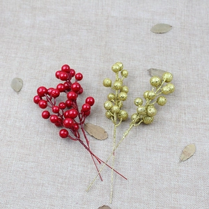 Artificial red and gold Christmas berry stems displayed on rustic linen background