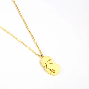 Detailed macro view of 18K gold-plated abstract face pendant on minimalist necklace