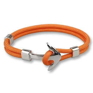 Macro detail of orange woven rope bracelet with silver anchor clasp on white background