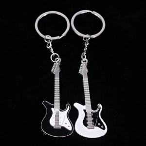 Juego de dos llaveros de guitarra en esmalte blanco y negro sobre un fondo negro liso