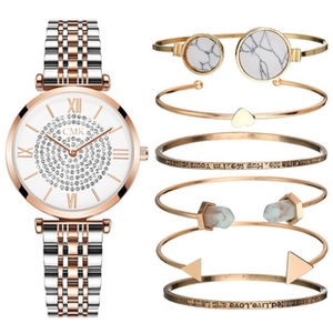 Detail of rose gold jewelry set featuring crystal watch and marble finish open bangles