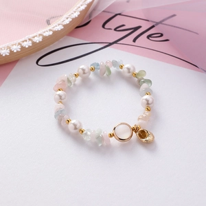 Macro detail of handmade elastic bracelet with irregular shells, pearls and gold charms