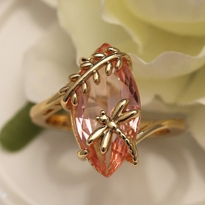 Elegant gold dragonfly ring featuring a large marquise-cut orange gemstone centerpiece