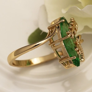 Detail of gold ring with large oval green gemstone and delicate vine leaf setting
