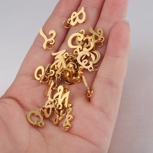 Hand holding a collection of gold stainless steel alphabet charms with small jump rings