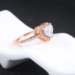 Detail of rose gold heart ring with halo-set cubic zirconia on a white stand