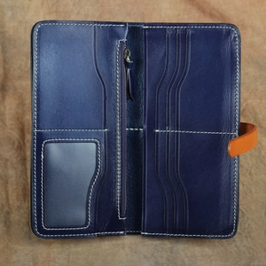 Dettaglio portafoglio in pelle blu con fibbia arancione e scomparti per carte