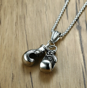 Detailed view of a silver boxing glove pendant with metal chain on a wooden surface