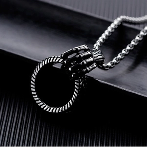 Detail of gothic silver-tone claw pendant holding a textured ring on a thick metal chain