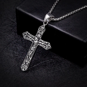 Detailed close-up of a silver crucifix pendant with religious relief on a box chain