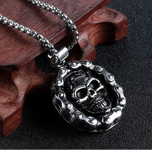 Close-up of hip hop skeleton skull pendant with vintage silver chain on dark wood