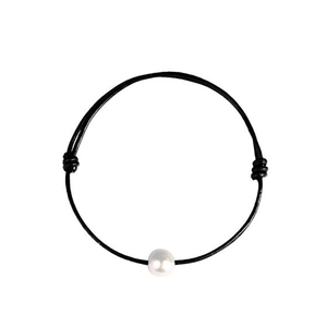 Detailed view of a black leather cord bracelet featuring a single white freshwater pearl