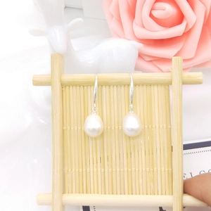 Detail of drop-shaped freshwater pearl earrings with silver hooks on decorative display